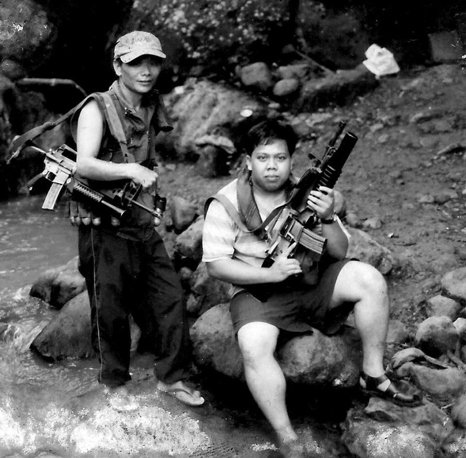 ARMED. The author as a young reporter in the 90s holding an AR 15 assault rifle takes a souvenir shot with an NPA Red fighter. | Photo taker unknown