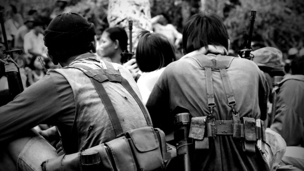 COMRADES IN ARMS. Two Red fighters of the CPP New People’s Army with ammo watches a cultural presentation during celebrations for the founding of the Communist Party of the Philippines more than a decade ago in Negros island, Philippines. This was originally shot using colored film. | Photo by Julius D. Mariveles