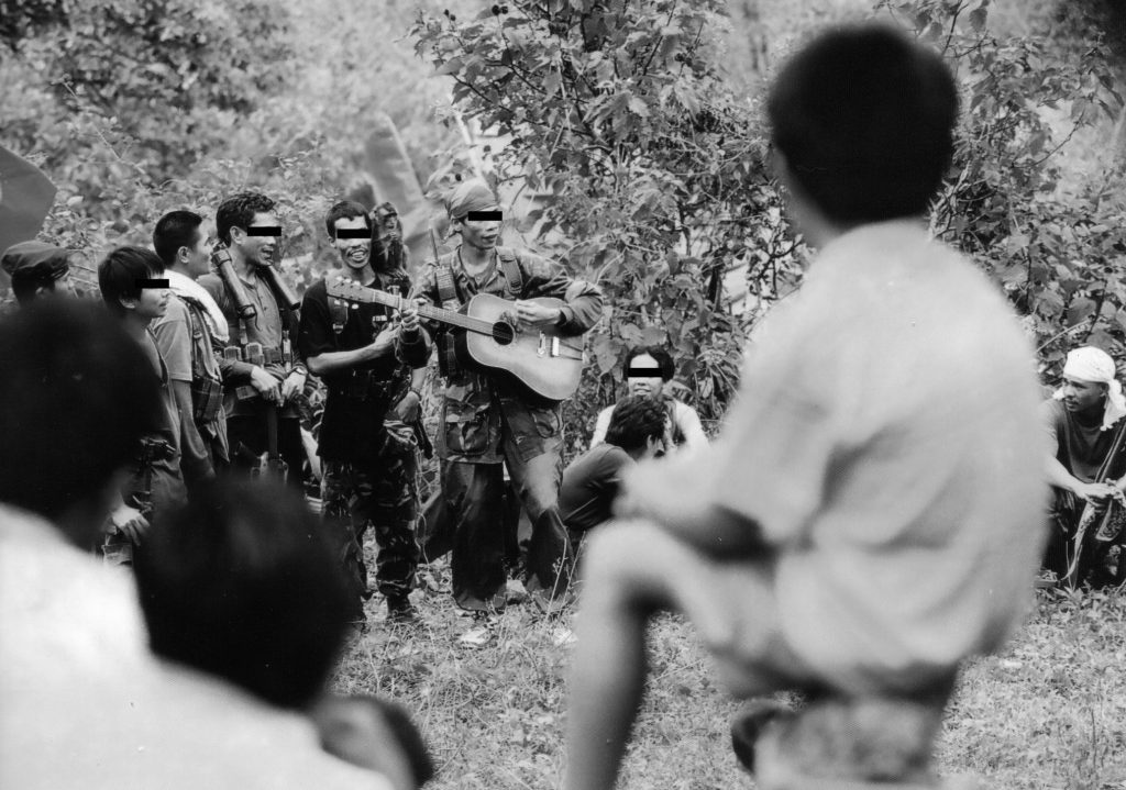 SINGING WARRIORS | Red fighters of the New People’s Army play a guitar and sing revolutionary songs during a celebration of the Communist Party’s founding anniversary in Negros island, Philippines | The CPP is the political wing of the NPA | This was originally shot using colored film | Photo by Julius D. Mariveles