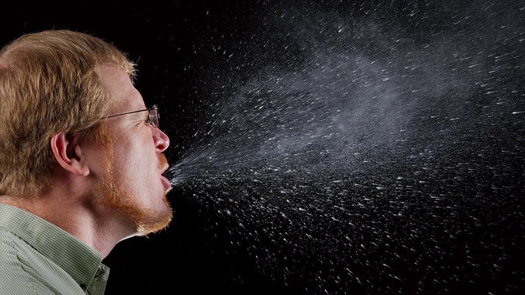 "This 2009 photograph captured a sneeze in progress, revealing the plume of salivary droplets as they are expelled in a large cone-shaped array from this man’s open mouth, thereby dramatically illustrating the reason one needs to cover his/her mouth when coughing, or sneezing, in order to protect others from germ exposure." | Photo by James Gathany / Public domain